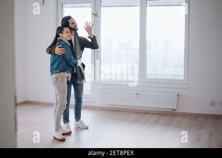 Jeunes propriétaires de couple qui s'embrasent dans un nouvel appartement, qui se déplace dans, nouveau concept de maison et de déménagement. Banque D'Images