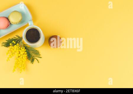 Tasse à café avec macarons et fleurs jaunes sur fond jaune. Copier l'espace. Vue de dessus. Concept de ressort. Banque D'Images