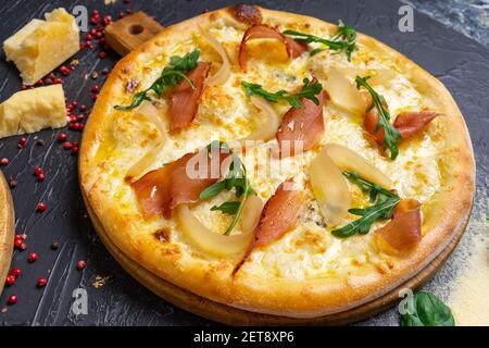 Pizza au prosciutto (jambon de parme), arugula (roquette à salade) et parmesan sur fond de bois foncé. Cuisine italienne. Banque D'Images