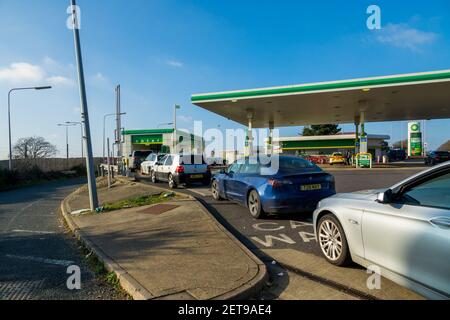 Une file d'attente de voitures au lave-auto automatique sur une piste de station-service BP un dimanche après-midi ensoleillé. Banque D'Images