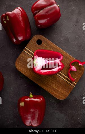 Poivrons verts suén sur planche à découper en bois sur fond noir et gris foncé. Poivron vert tranché et haché sur une planche à découper en bois. Poivre vert Banque D'Images