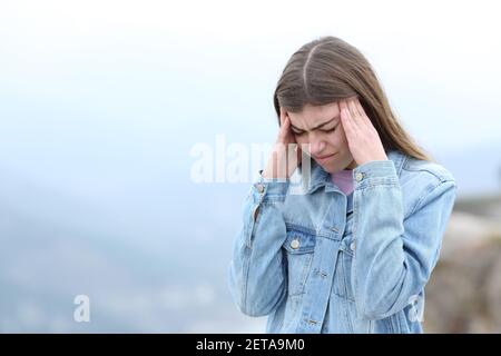 Femme stressée souffrant de migraine dans la montagne Banque D'Images