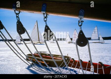 COURSE DE BATEAUX À GLACE DES ANNÉES 1980 VUE À TRAVERS LES FEUILLES ET LES POULIES FIXÉ AU BAS DE LA PERCHE DE VOILE ESTURGEON BAY WISCONSIN USA - KW8927 VRE001 HARS AVENTURE ET EXCITATION BASSE ANGLE DE LOISIRS NOUS NOUS REPLAGIONS SUR LES POULIES DE RAMPE D'HIVER DE L'ESTURGEON Banque D'Images