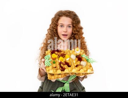 Belle adolescente aux cheveux rouges avec des boucles afro ondulées tenant un panier de Pâques maison avec des poulets et des œufs en studio sur fond blanc. Fermer Banque D'Images