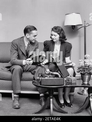 ANNÉES 1930 ANNÉES 1940 JEUNE COUPLE DATANT HOMME ET FEMME ASSIS SUR LECTURE DE LA MUSIQUE SUR LE LECTEUR D'ENREGISTREMENT PORTABLE - S8949 HAR001 HARS COUPLE NOSTALGIQUE ROMANCE BEAUTÉ SUBURBAIN URBAIN VIEUX TEMPS NOSTALGIE MÉDIAS VIEILLE MODE 1 STUPIDES COMMUNICATION DE CANAPÉ JUVÉNILE JEUNES ADULTES ÉQUILIBRE COMIQUE TRAVAIL D'ÉQUIPE FORTE HEUREUX JOIE STYLE DE VIE FEMMES ACCUEIL VIE LUXE COPIE ESPACE AMITIÉ PLEINE LONGUEUR DAMES PERSONNES ATTENTIONNÉES GARÇONS ADOLESCENTE ADOLESCENT GARÇON DIVERTISSEMENT PORTABLE B&W DATANT TENTATION BONHEUR HUMORISTIQUE GAI LOISIR ET CHOIX EXCITATION RÉCRÉATION COMIQUE INNOVATION ON POUR SOURIRE LA CONNEXION À 78 TR/MIN Banque D'Images