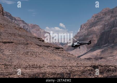 Un hélicoptère survolant le magnifique Colorado Grand Canyon avec un contraste saisissant entre l'hélicoptère, les montagnes et le ciel. Banque D'Images