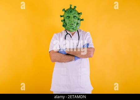 Médecin - infirmière en coronavirus déguisée portant un masque en latex - virus Covid-19 avec bras croisés sur fond jaune. Concept de coronavirus Banque D'Images