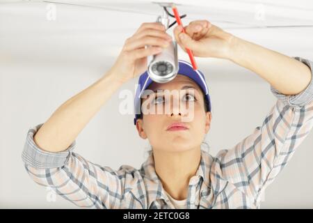 Female electrician l'installation de lumières au plafond Banque D'Images