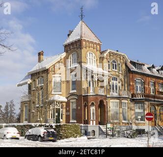 ZUTPHEN, PAYS-BAS - 10 février 2021 : architecture Art nouveau de maisons de maître colorées en hiver avec de la neige dans les rues et sur les toits bordés Banque D'Images