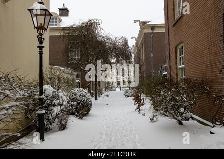 ZUTPHEN, PAYS-BAS - 08 févr. 2021 : allée menant à l'utilisation de café cour jardin dans le centre historique de la ville hanséatique médiévale pendant un Snowstor Banque D'Images