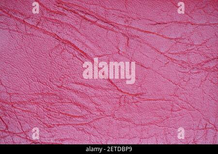 Un fragment de cuir véritable aux plis et aux plis, teint artificiellement dans une couleur rouge vif. Arrière-plan, motif, texture. Banque D'Images