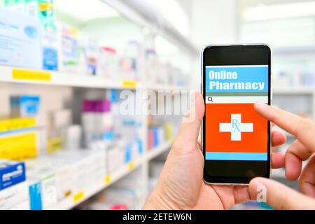 Pharmacien utilisant un téléphone intelligent mobile pour la barre de recherche sur l'affichage dans les étagères de pharmacie arrière-plan. Concept médical en ligne Banque D'Images