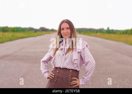 Une fille se tient sur la piste. Perspective dans la distance. Un jour d'été sombre. Banque D'Images