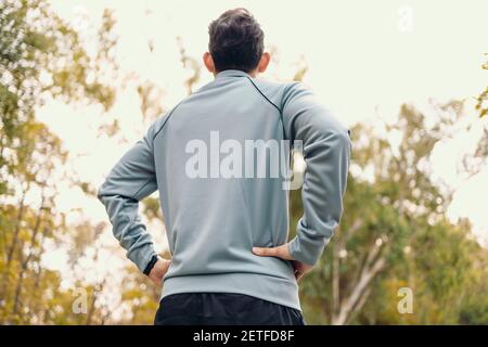 Un homme avec les mains à la taille et voir dans le ciel en veste après la course. Banque D'Images