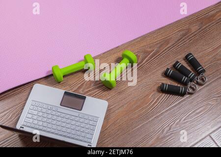 Tapis de fitness, haltères, extenseur et ordinateur portable pour les entraînements en ligne à la maison. Concept d'apprentissage en ligne en relation avec la pandémie Banque D'Images