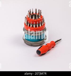 Un jeu d'outils de travail avec un tournevis et des embouts pour la réparation, dans une boîte en plastique ouverte avec des embouts en fer, à l'intérieur d'un tournevis. Banque D'Images