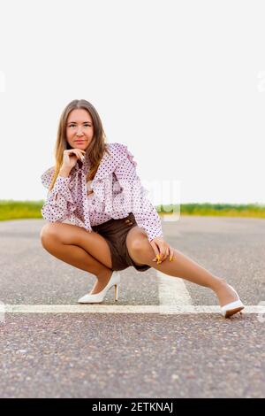 Une fille se tient sur la piste. Perspective dans la distance. Un jour d'été sombre. Banque D'Images