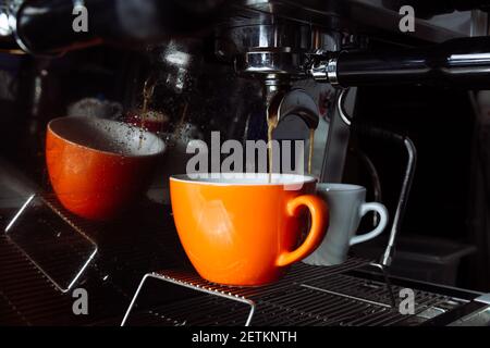 Le café fraîchement préparé est versé de la machine à café dans des tasses . Verser, boisson. Banque D'Images