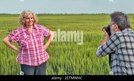 Le photographe photographie son modèle dans le jeune blé. Banque D'Images