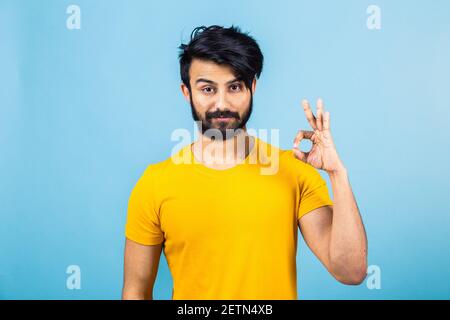 Portrait émotionnel d'un homme hindou dans un T-shirt jaune sur fond bleu vif Banque D'Images