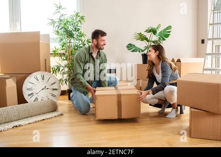 Mari et femme déballant des choses dans leur nouvelle maison avec sourit sur leur visage Banque D'Images