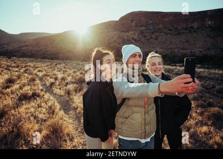 Groupe d'adolescents prenant le selfie sur l'aventure randonnée pédestre à travers scène de montagne Banque D'Images