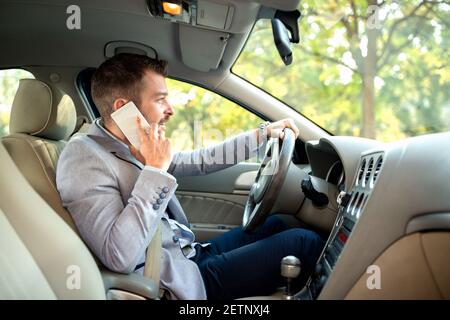 Jeune homme négligent parlant sur son téléphone mobile en conduisant Banque D'Images