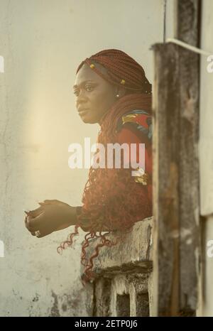 Femme africaine donnant sur la mer depuis un balcon Au coucher du soleil à Accra Ghana Afrique de l'Ouest Banque D'Images