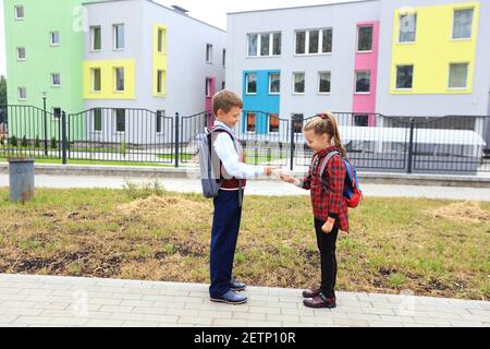 Enfants avec porte-documents sur leurs épaules sur le fond de l'école. Banque D'Images