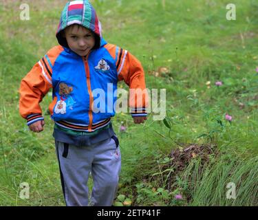 Adorable garçon avec des expressions du visage intéressantes et une allure inhabituelle dans un pré de fleurs. La photo a été prise près du lac Uvildy, région de Chelyabinsk, Russie. Banque D'Images