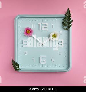 Horloge bleue avec fleurs sur les têtes, concept de l'heure du printemps. Le pastel colres un bel arrière-plan. Banque D'Images
