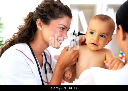 Pédiatre fournissant des soins de santé à son bébé patient dans le bureau d'une clinique spécialisée pour les enfants Banque D'Images