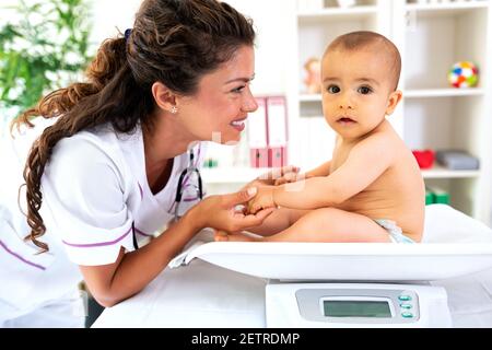 Juste un bébé mignon assis debout sur la mesure de poids périphérique Banque D'Images