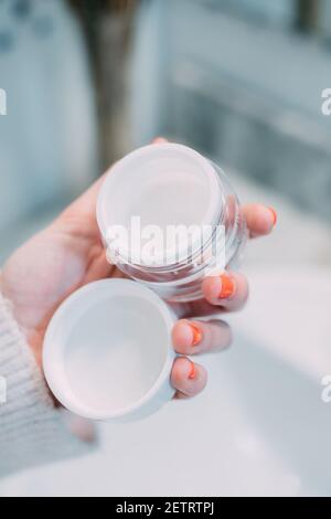 main d'une jeune femme tenant un pot de verre ouvert de crème pour le visage dans sa routine quotidienne. concept de soin et de beauté Banque D'Images