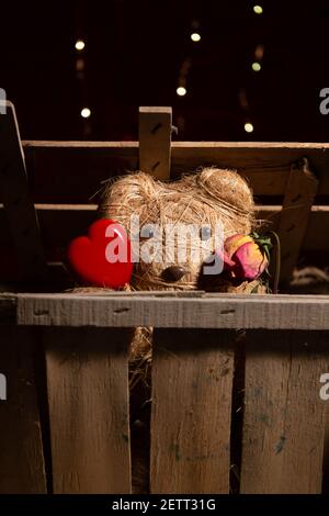 Adorable ours en peluche fait main avec un coeur en bois et un rose pâle Banque D'Images