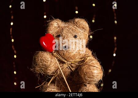 Adorable ours en peluche fait main avec un coeur en bois et un rose pâle Banque D'Images