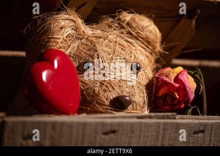 Adorable ours en peluche fait main avec un coeur en bois et un rose pâle Banque D'Images