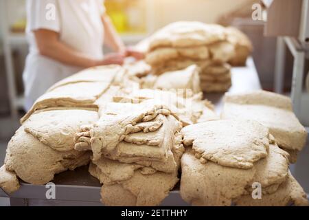 Une grande quantité de pâte est inspectée par un travailleur prudent dans des chiffons stériles avant de la traiter plus loin dans la chaîne de production alimentaire. Banque D'Images