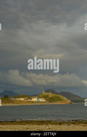 Criccieth éclairé par la lumière du soleil pour la plage à Llanystumdwy avec les collines de Snowdonia sous les nuages de tempête. Banque D'Images
