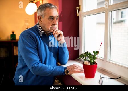Un vieil homme malade senior regardant par la fenêtre, restant seul à l'allaitement accueil Banque D'Images