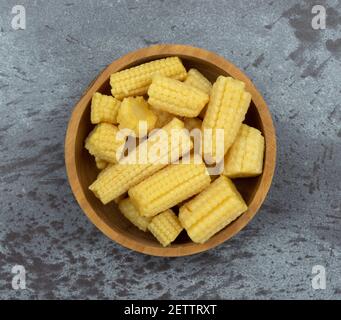 Vue en hauteur d'un bol en bois rempli de maïs biologique en conserve sur fond gris marbré. Banque D'Images