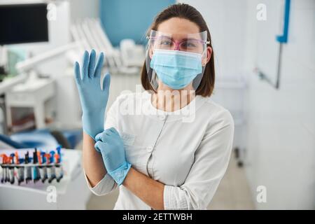 Une femme excitée tire sur un gant médical bleu Banque D'Images