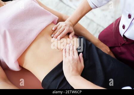 Macro close up de thérapeute de massage viscéral faisant mains sur l'abdomen des femmes. Banque D'Images