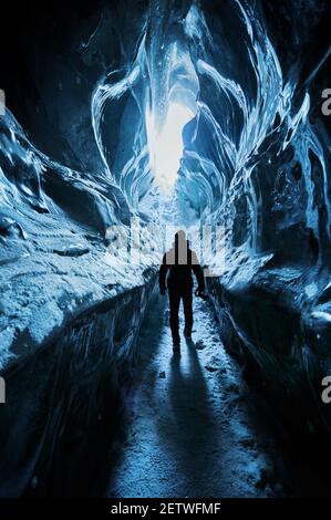 Silhouette d'homme explorant une incroyable grotte de glace glaciaire dans Les montagnes au Kazakhstan Banque D'Images