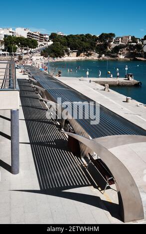 Un coin salon couvert et moderne au bord du quai projette des ombres intéressantes au soleil de midi à Porto Christo, Majorque. Banque D'Images