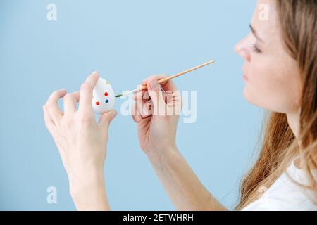 Gros plan photo, femme peinture oeuf de pâques, à l'aide d'un pinceau. Banque D'Images