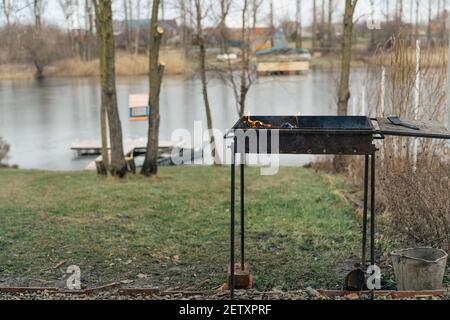 brazier cuisine extérieure petit bateau de feu de rivière en arrière-plan et les arbres Banque D'Images