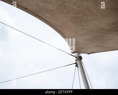 Câble métallique en acier soutenant au point de traction connexion sur le poteau de l'ancien toit en toile d'extérieur blanc sur fond ciel avec espace de copie. Banque D'Images