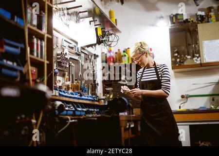 Femme professionnelle qui travaille à polir les équipements de vélo dans l'atelier. Banque D'Images