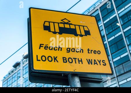 Dublin, Irlande, la signalisation de signe REGARDENT LES DEUX MANIÈRES en anglais et en irlandais langue gaélique. Avertissement pour le tramway LUAS système de transports publics dans la capitale. Banque D'Images